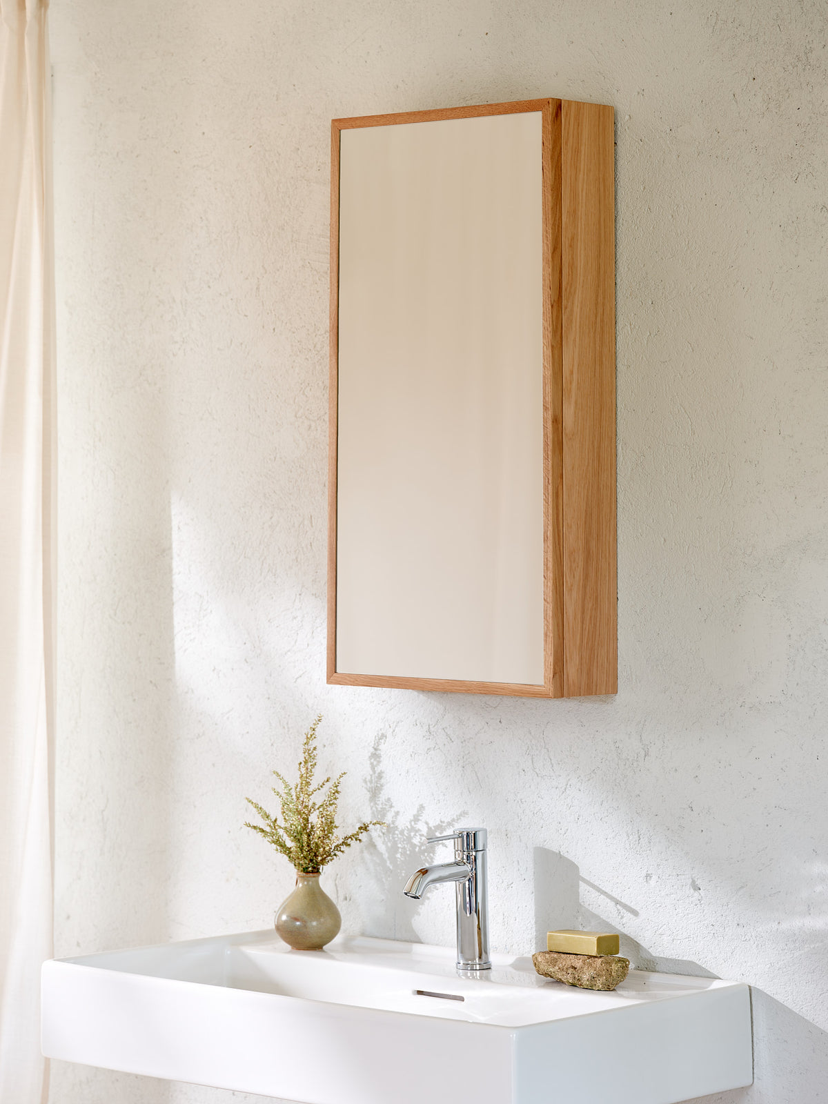 Natural oak wall-mounted mirror cabinet above a bathroom sink